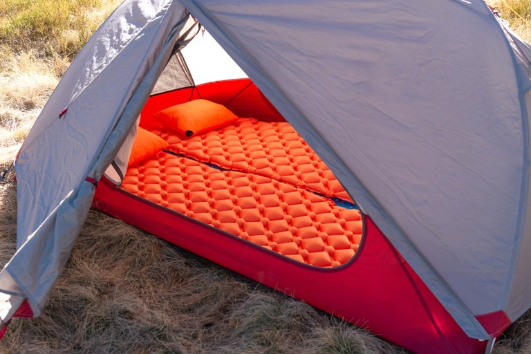 A pillow and sleeping pad in a tent.