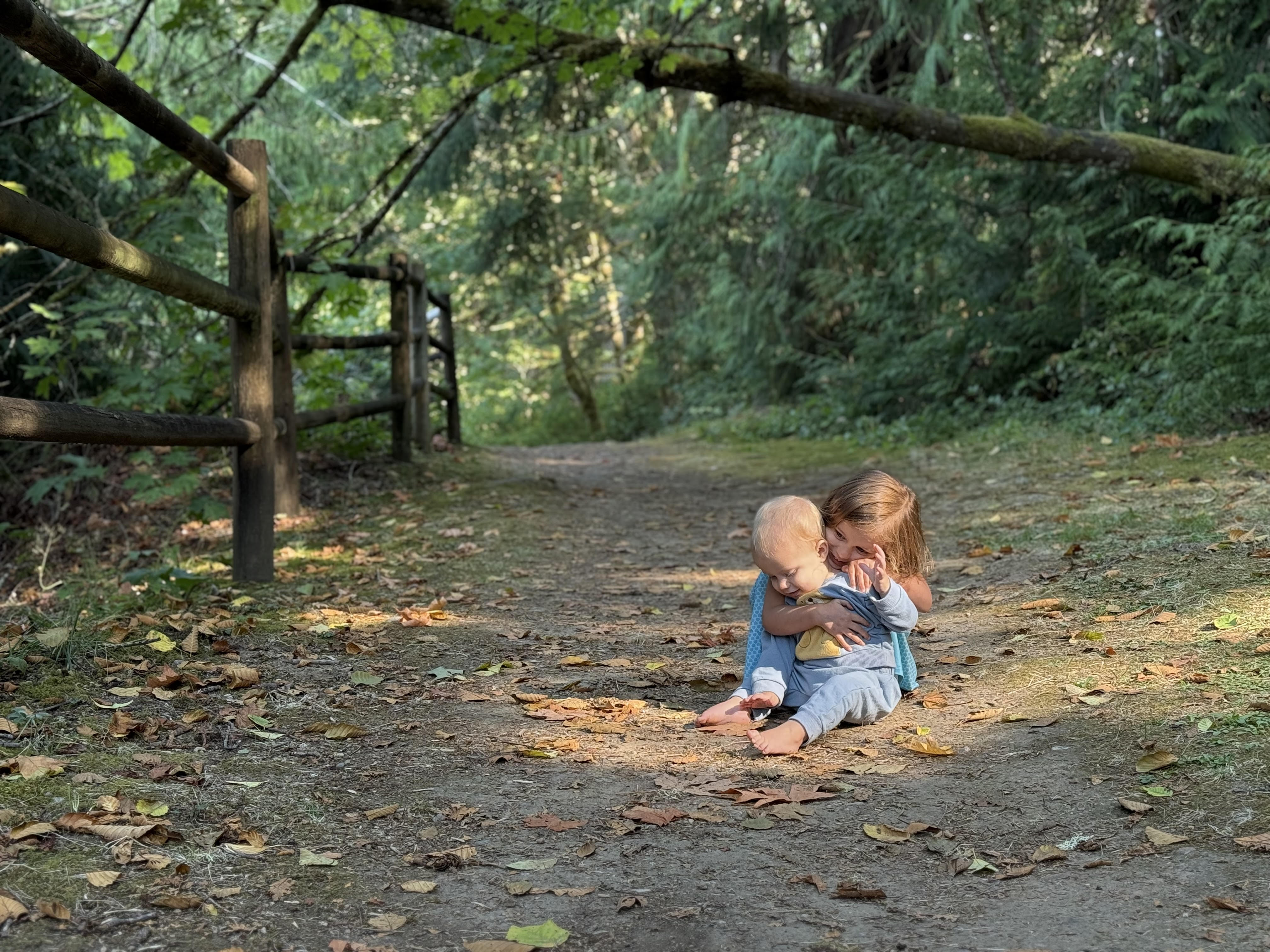 Two children embrace on a sunny day on trail.