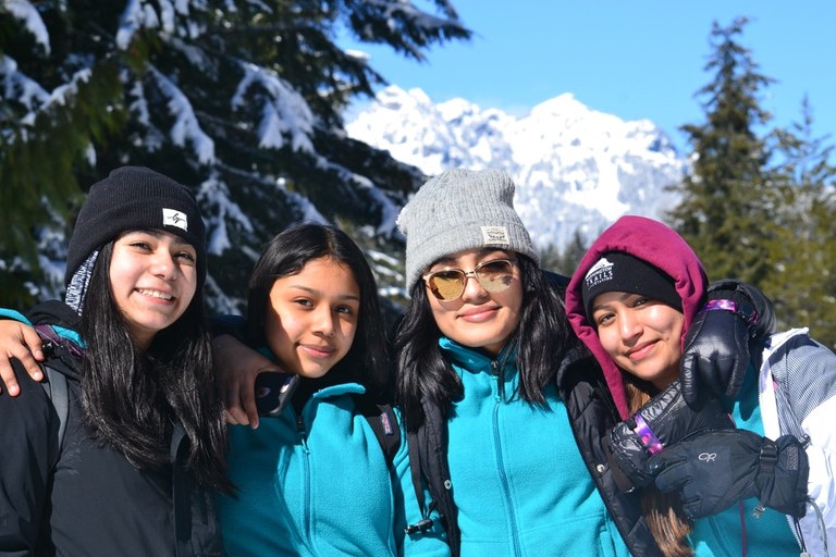 Four youth smile from a snowy trail.