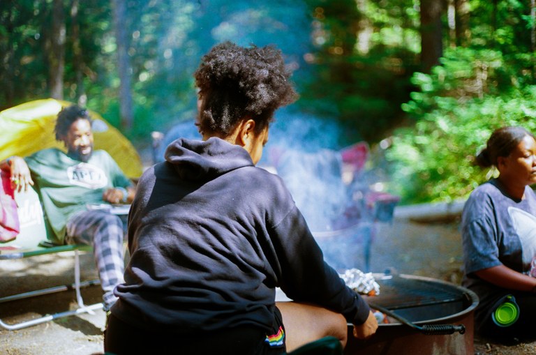 Cougar Rock Campground Campers sit around a fire ring in an established campground.