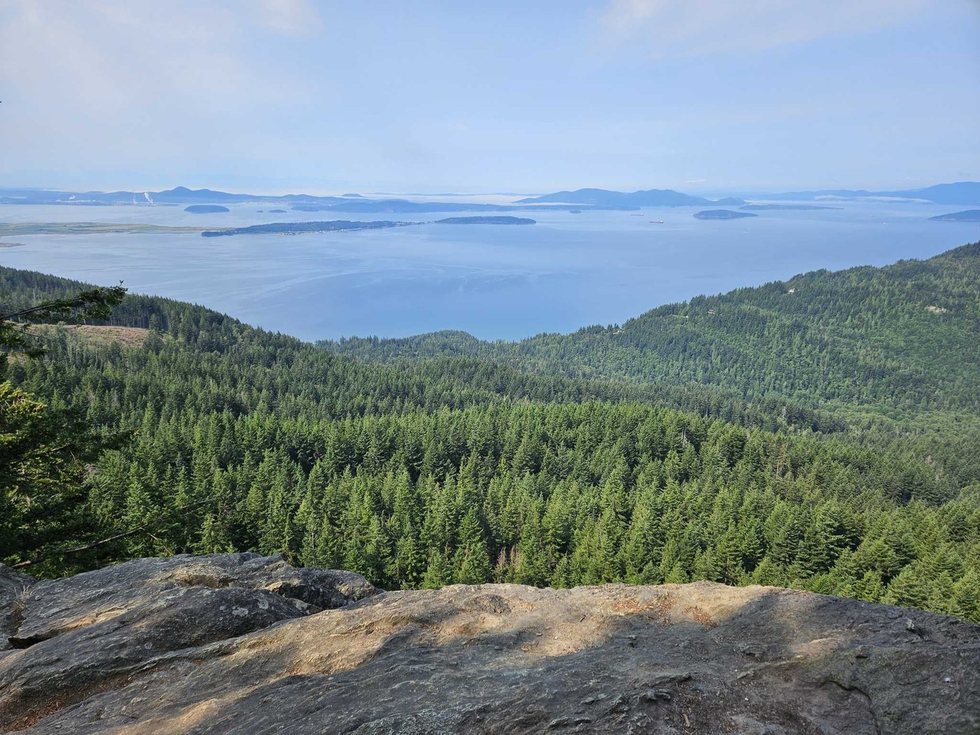 Rocky ledge overlooking evergreen trees and water dotted with islands