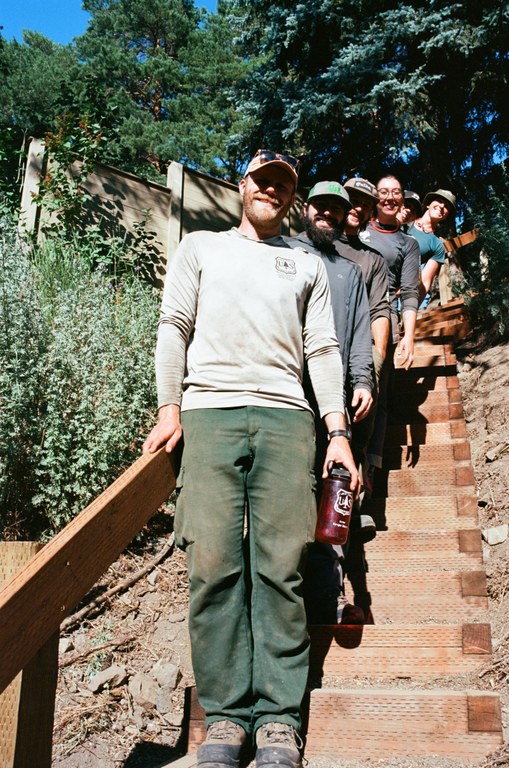 WTA's Eastern Washington professional crew spent 3 hitches building the structure. Photo by Joe Hall A crew of trail workers stand on a new wooden staircase. They are staggered by steps.