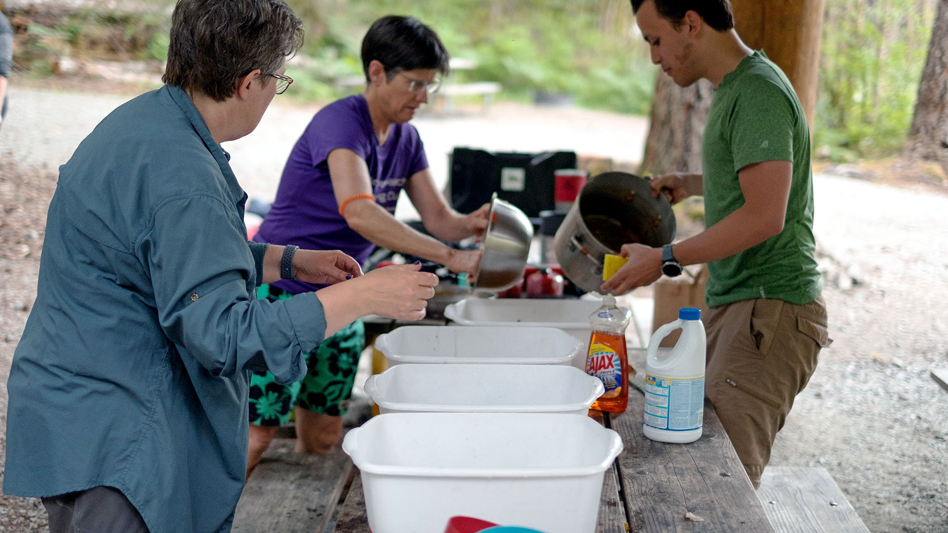 Campers wash dishes in plastic bins