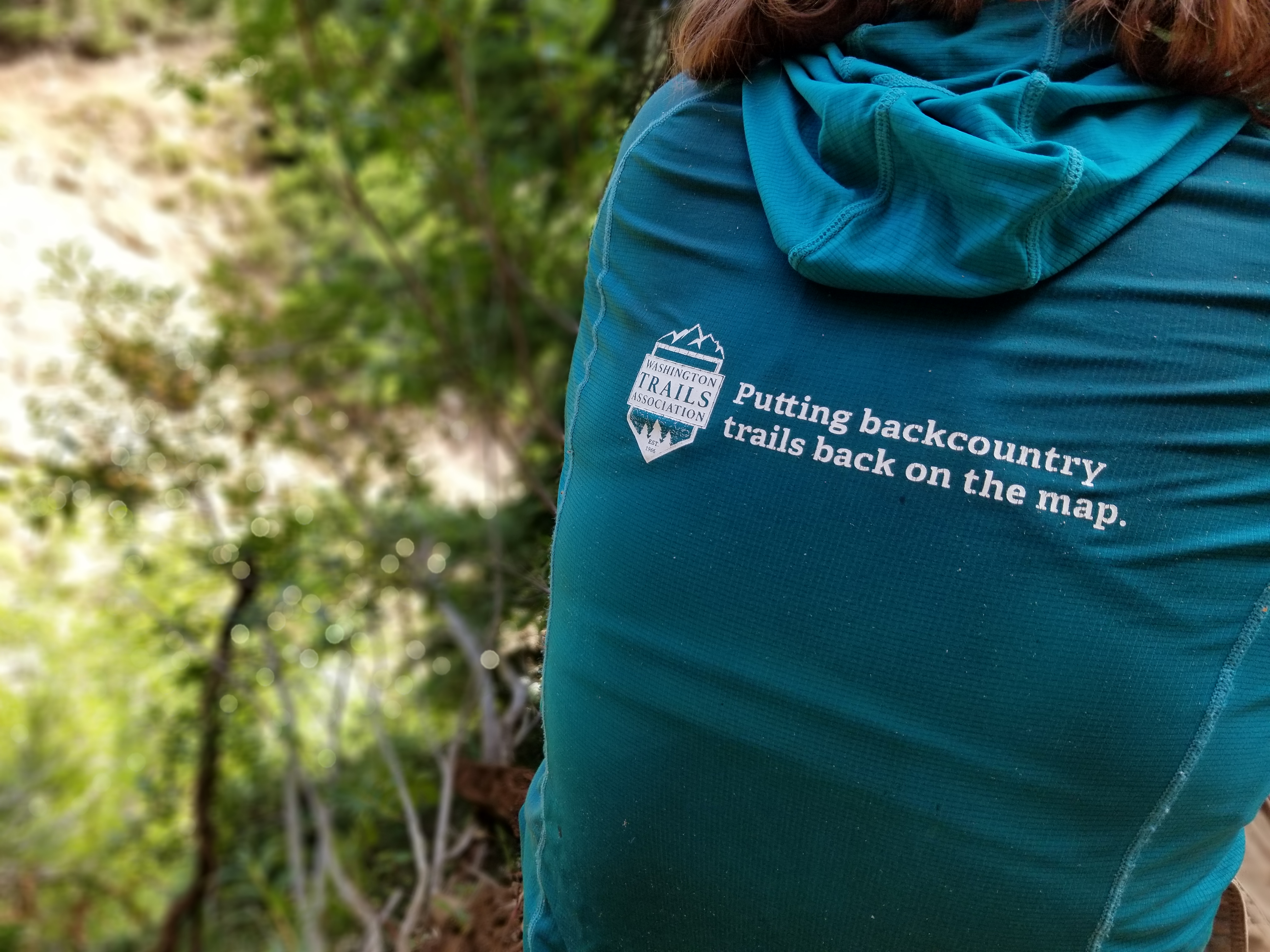 A WTA LTF crewmember wears a hoodie that reads "putting backcountry trails back on the map"