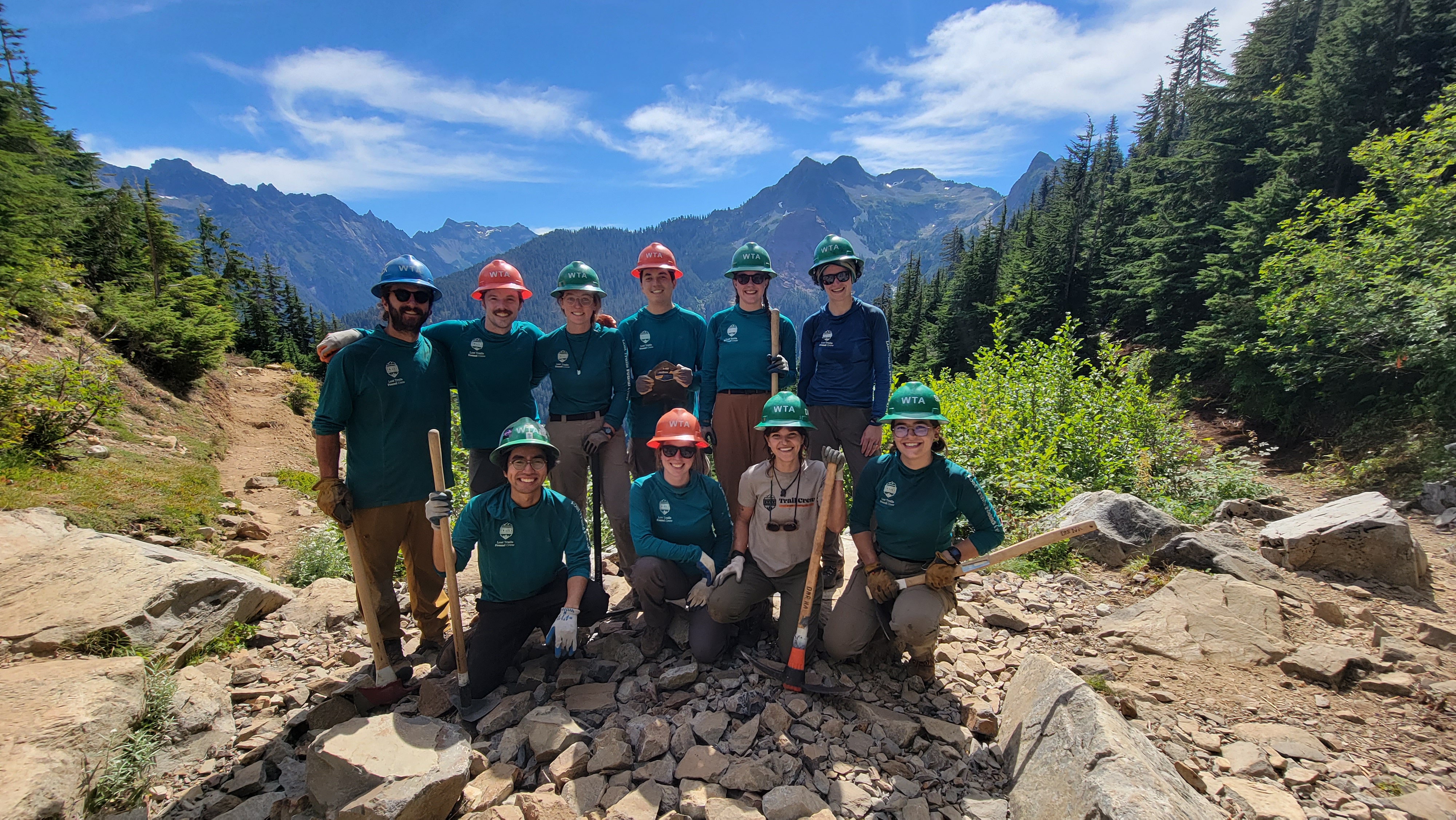 Lost Trails Found crewmembers pose for a photo before a mountain backdrop.