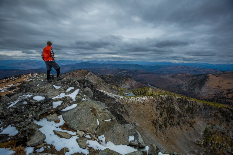 Hiker in orange A hiker in an orange vest stands on a peak