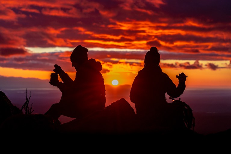 silhouettes of hikers eating on mountain