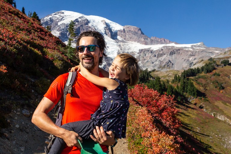 child and parent hiking with mountain in background