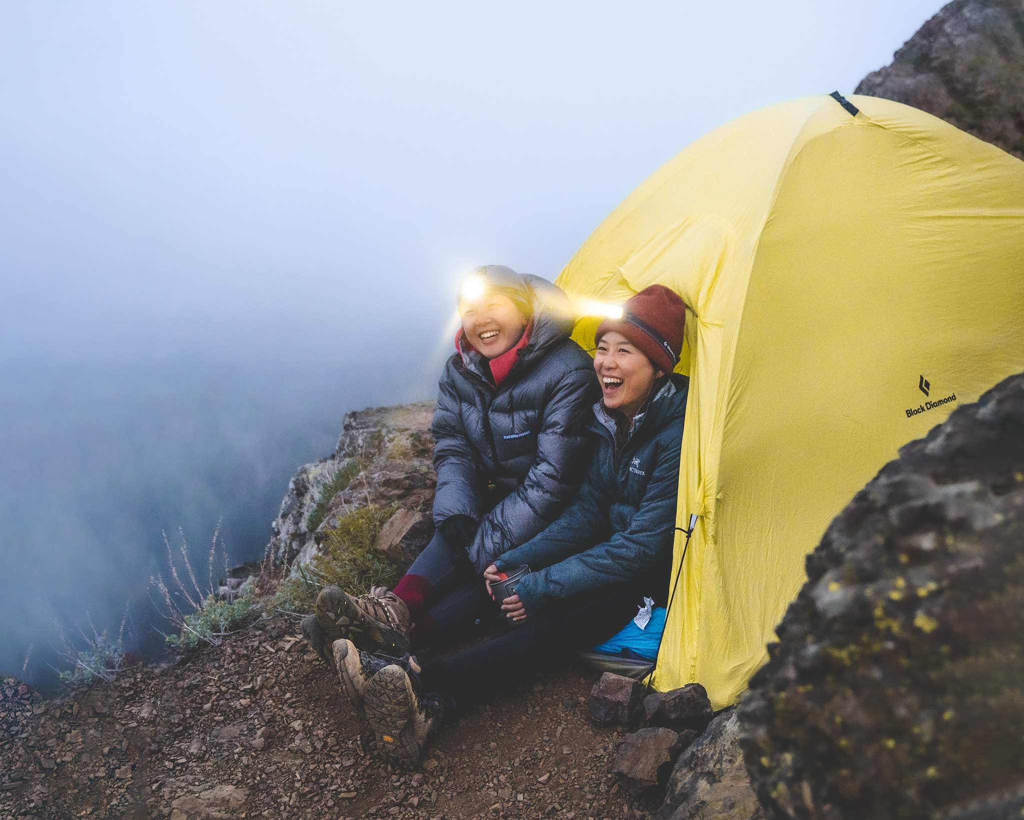 Photo by Charles Wang Two hikers camping next to tent on mountain