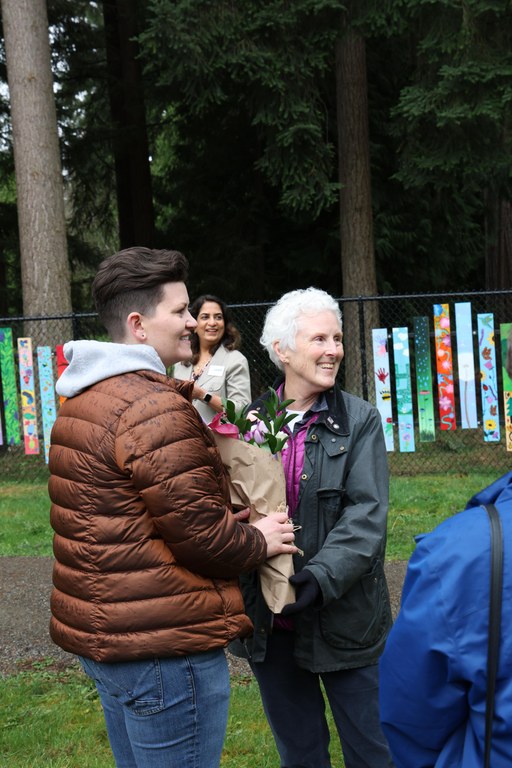 Mayor Kali Clark passes bouquet of flower wrapped in brown paper to Mary Pigott.