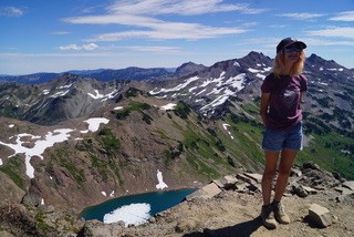 Image: Lu with an alpine lake in the background. Photo by Lu Martin.