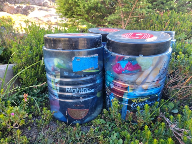 Bear canisters on the ground filled with food. Photo by Joe Gonzalez. 