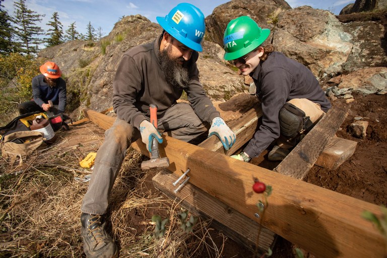 WTA crews work to assemble a wooden structure on trail. 
