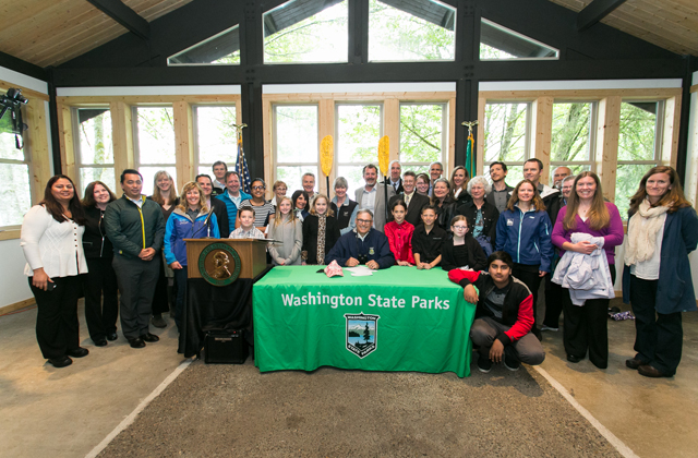 Governor Inslee signs landmark recreation legislation on May 13, 2015 as WTA's Andrea Imler (blue jacket, third from right) and other recreation partners look on. Photo credit Legislative Support Services. 
