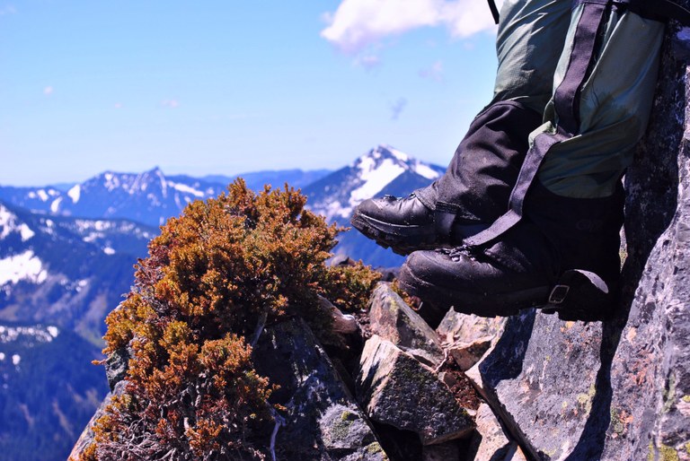 Boots in foreground. Blue, sunny skies and mountains in background.