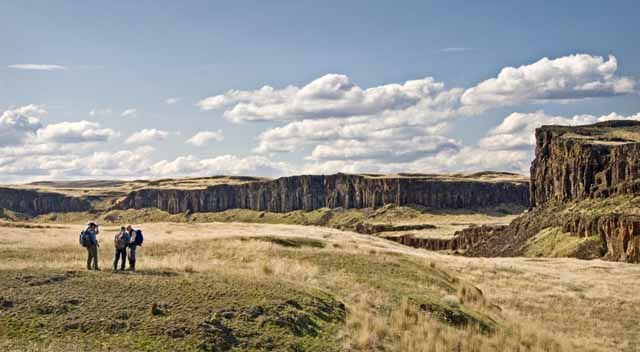 A small group of people in the foreground, with a landscape of canyons in the background