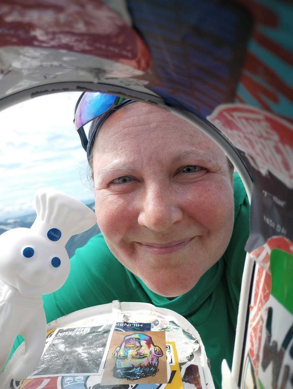 A hiker and a toy Pilsbury Doughboy look inside a mailbox.