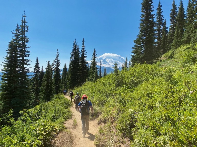 A WTA trail crew hiking on the trail with Mount Rainier in the background. Photo by Dan Hagberg. 