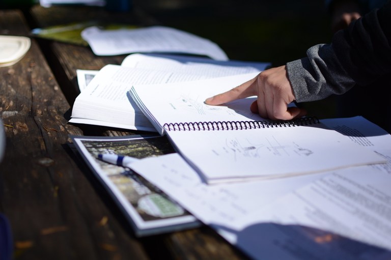 A trainer points at a trail work diagram spread out on a table. 