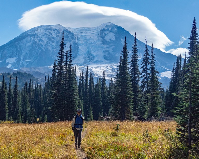 Divide Camp Trail A hiker walks down a trail with Mount Adams rising high in the background.