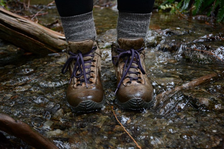 A paid of waterproof boots standing in a shallow stream.