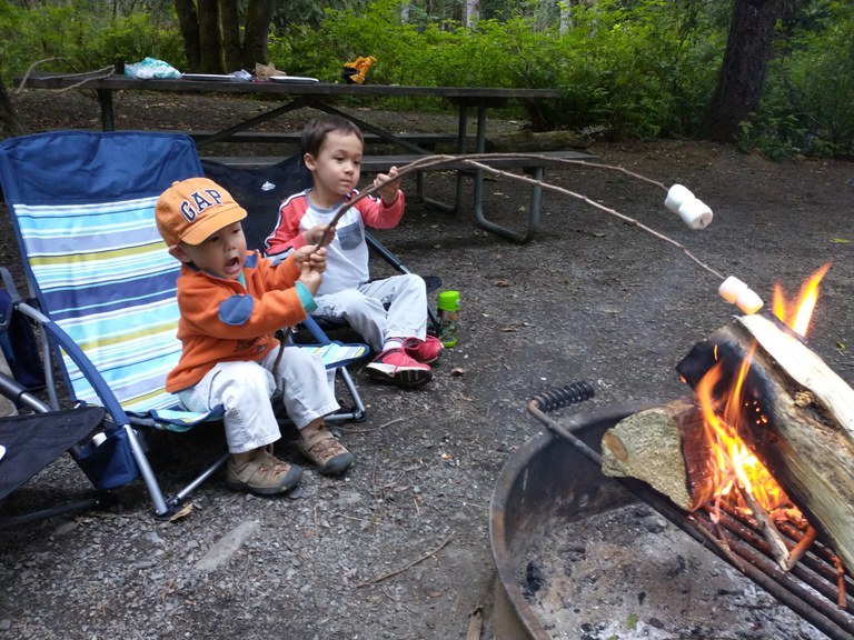 Two young campers roast marshmallows over a fire. 