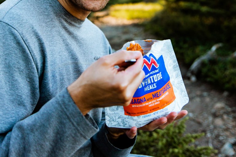 Mountain House A hiker eats a spoonful of a Mountain Hose meal while on trail.