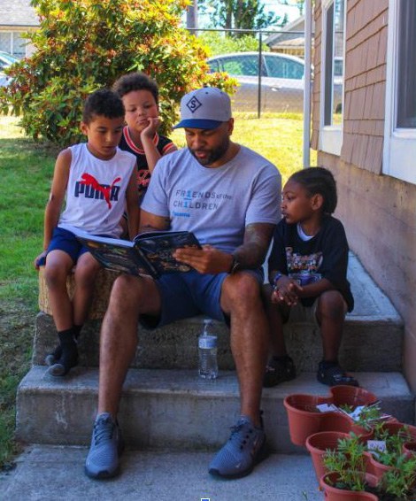 Friends An adult reading to several children on a porch.