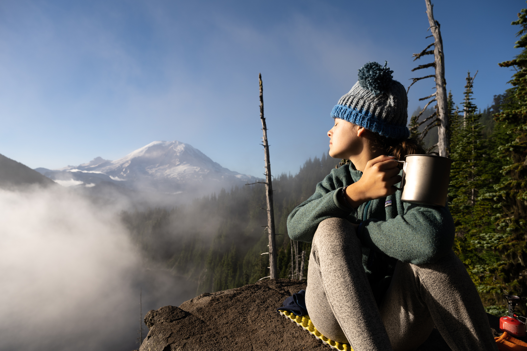 hiker with face in sun and hot cocoa mt rainier in background - Photo by Matthew Johnson