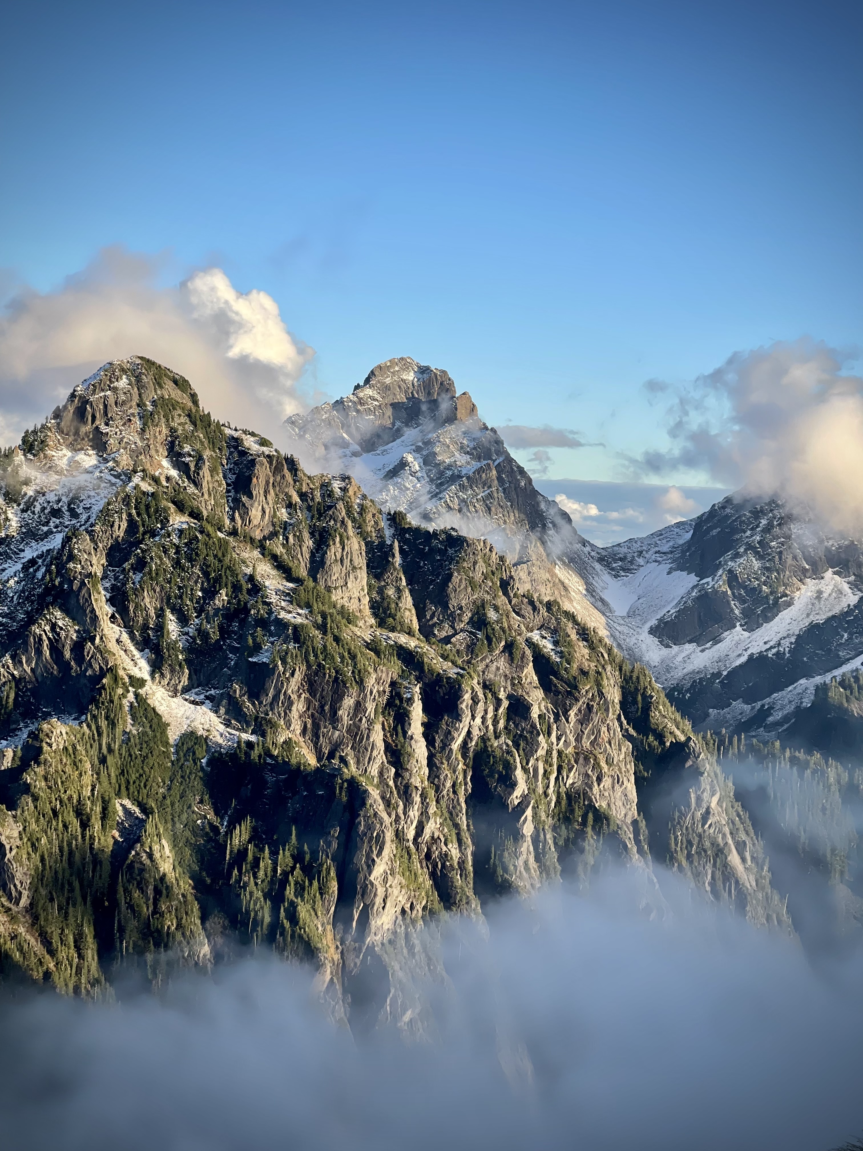 Photo by Elanie Igama Mountain peaks with clouds in sunlight.
