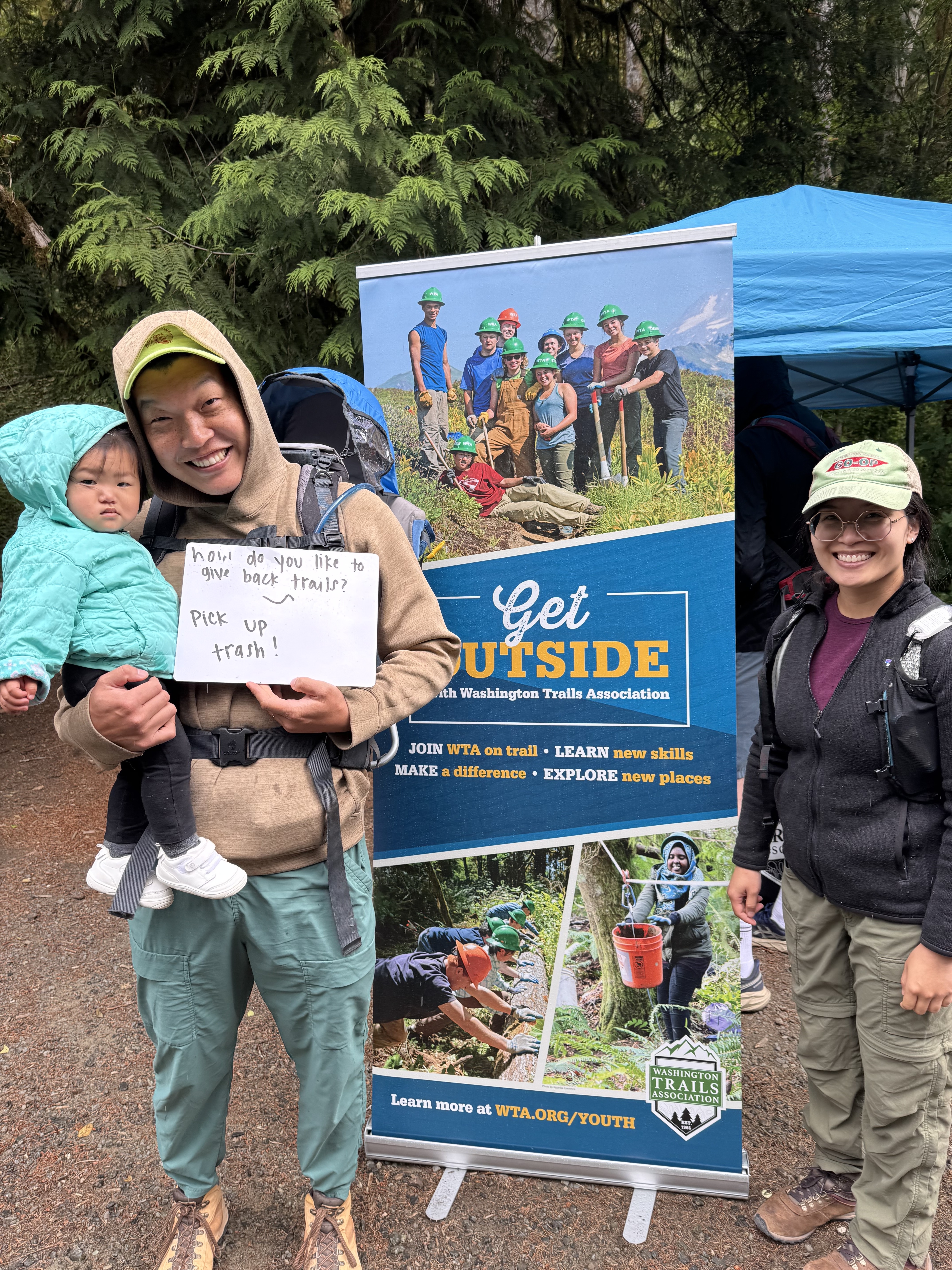 Family with baby talks holds sign about how they plan to give back Family with baby talks holds sign about how they plan to give back