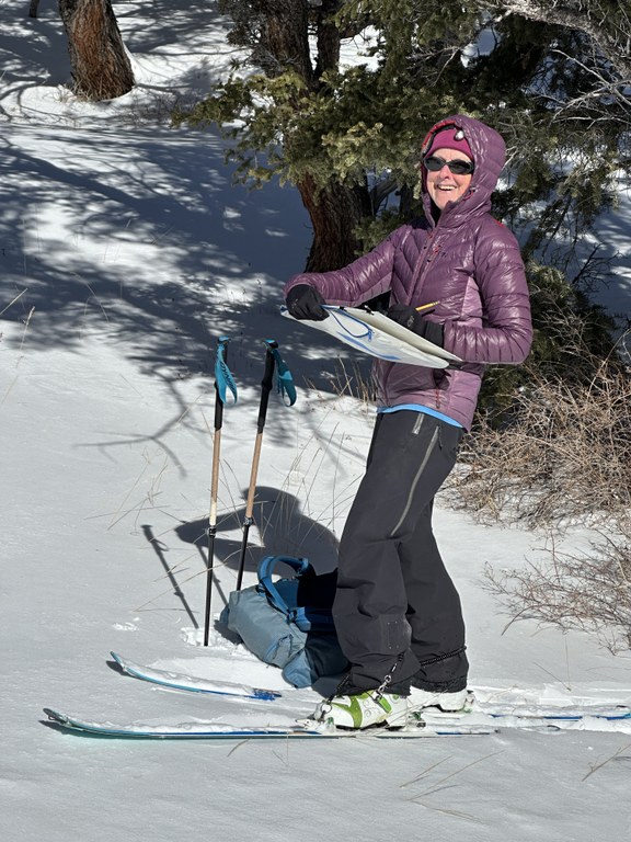Suze Woolf holding a painting in progress while skiing.