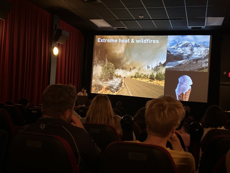 An image of a wildfire, ice cream cone and mountain project on a big screen. 