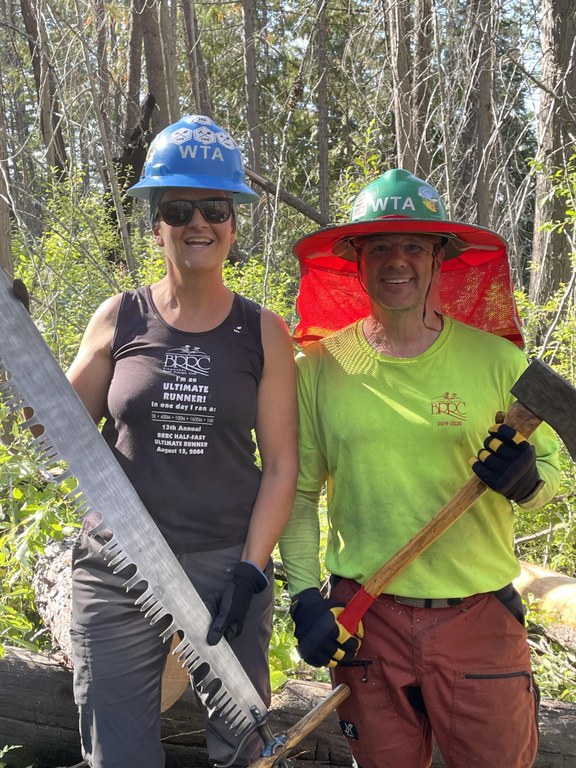 A WTA crew leader and volunteer pose with tools in hand.