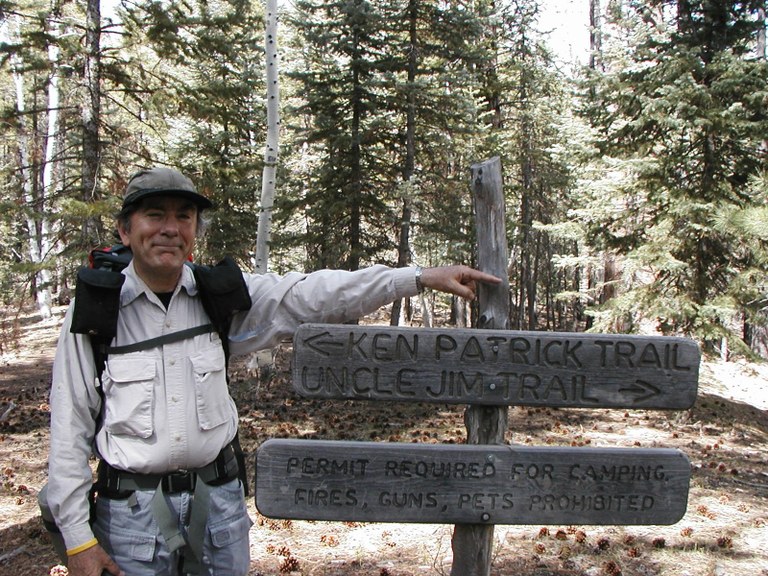 Jim Cavin stands next to a trail sign in the wilderness.