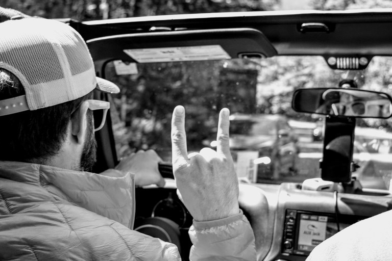 A man is having a great time driving a car on a sunny day. 
