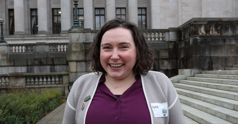 Katie From A hiker smiles at the camera in front of the state capitol.