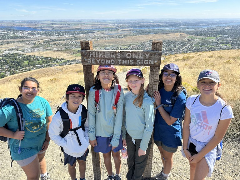 6 kids in front of a sign that says "hikers only beyond this sign." 