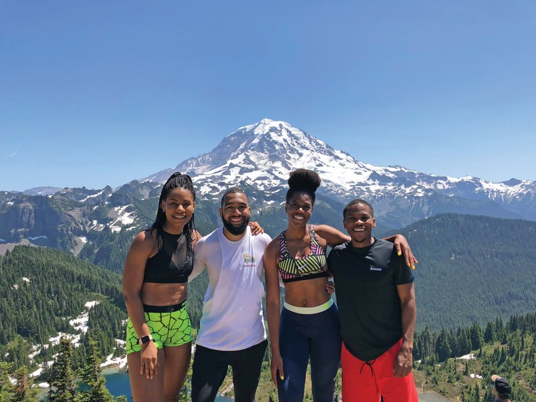 Four hikers from Miles Hike Club pose at a mountain view.