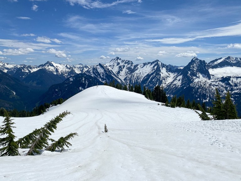 A snowy slope with distant snow-covered mountains. 