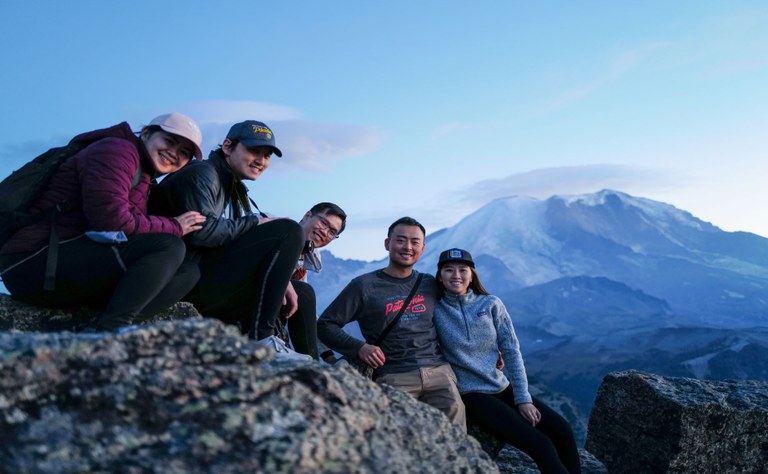 Mount Fremont A group of hikers arranged on a rock smile at the camera, with Mount Rainier behind.