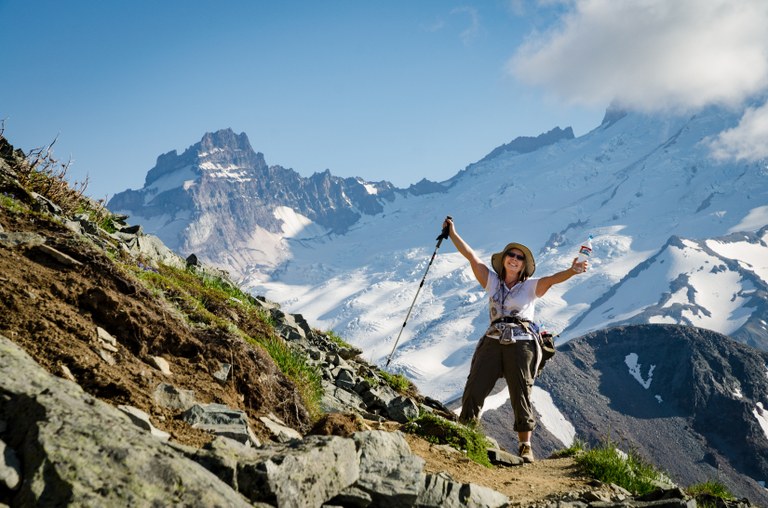 hiker smiling with mountains in the background.