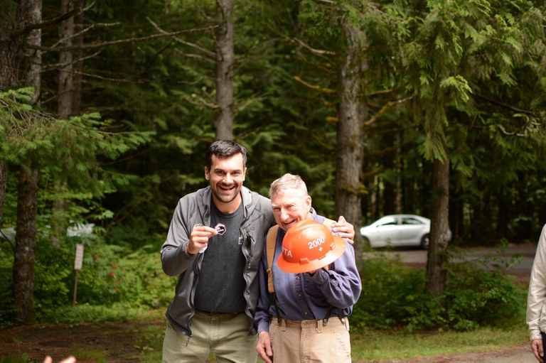 Pete Dewell smiles as he holds his orange hard hat and is presented with a custom 2000 sticker.