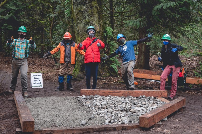 youth trail work A group of volunteers pose for a photo on trail. All are wearing masks and hard hats.