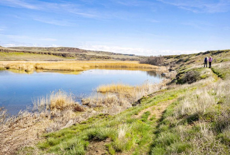 Two hikers next to Lake Lenice along the Palouse to Cascades Trail - Crab Creek on a sunny day. Photo by David Hagen/trip reporter mytho-man.