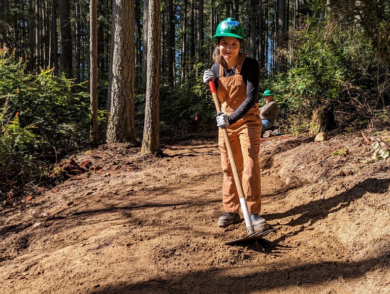 A volunteer poses on newly-built trail