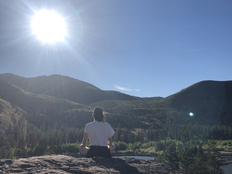 A hiker sits quietly facing the sun on a rock. Photo by Sarah Williams. 
