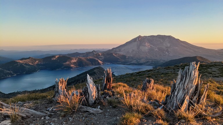Photo of Mt Helens and lake with purple and orange sunset.