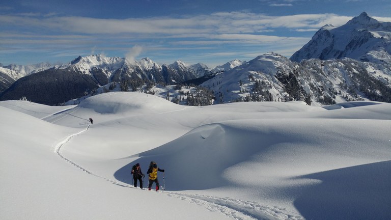 A person snowshoes across a flat snowy landscape. 