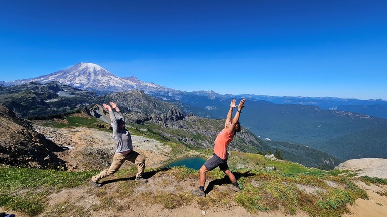Tatoosh Wilderness BCRT. Photo by James Alexander. Two crew members do yoga poses in front of Mount Rainier on a backcountry response team work party in the Tatoosh Wilderness. Photo by James Alexander.